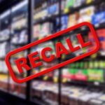 "Recall" stamp over blurred grocery store shelves.