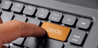 Finger pressing a cancel button on a keyboard.
