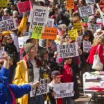 Protesters holding signs about unions and saving the American dream.