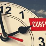 portion of an analog clock with hour hand pointing to 2 pm, with the word CURFEW