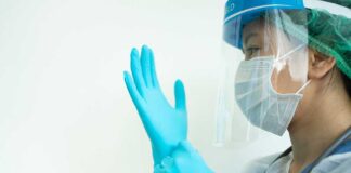 Medical worker putting on blue gloves.