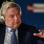 George Soros on headphones in front of a microphone.