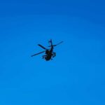 Silhouette of a helicopter against clear blue sky.