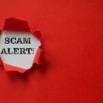 Scam alert text revealed through torn red paper