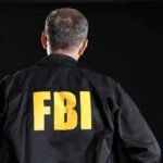 Person wearing jacket with "FBI" printed on back.