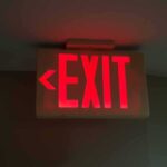 Illuminated exit sign with arrow pointing left.