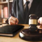 Another Judge Blocks Trump, Sparks Legal Showdown Gavel judges hand glasses and book on desk