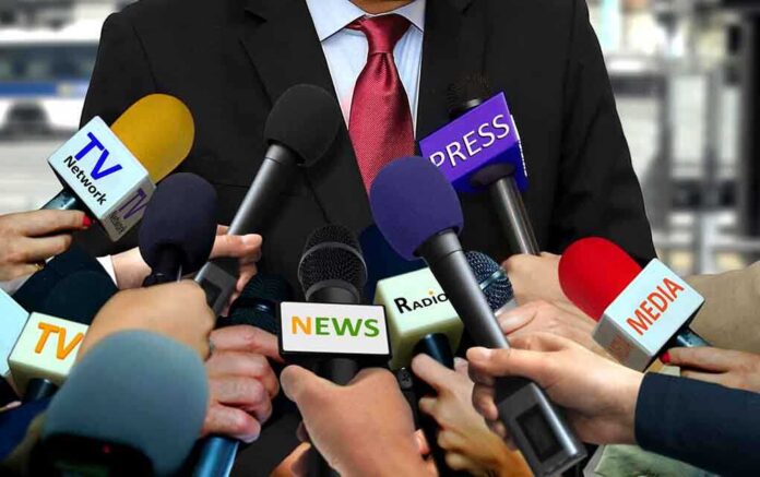 1096799972 featured image Person surrounded by microphones from various media.