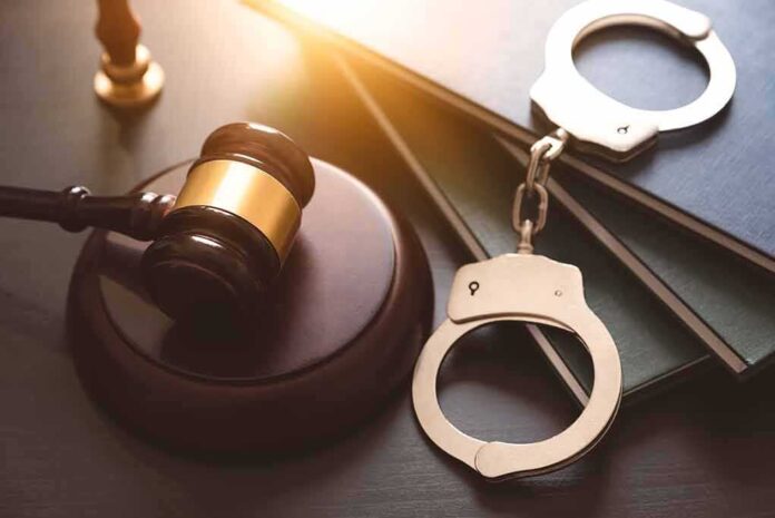 2142035749 featured image Gavel, books, and handcuffs on a table.