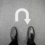 Feet in black shoes facing U-turn road marking