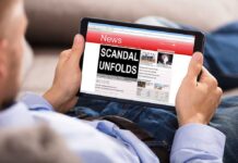 Person reading tablet with headline scandal unfolds