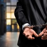 Person in handcuffs wearing a suit in office