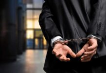 Person in handcuffs wearing a suit in office
