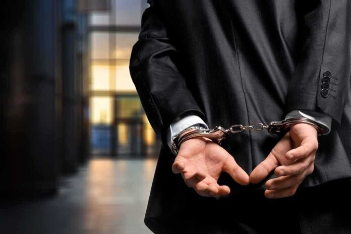 1182595936 featured image Person in handcuffs wearing a suit in office