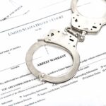 Handcuffs on an arrest warrant document