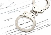 Handcuffs on an arrest warrant document