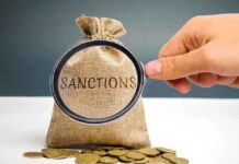 Hand holding magnifying glass over sack labeled Sanctions