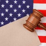 Judge’s Past Raises Questions About Impartiality, Conflict of Interest Gavel on American flag with blank paper