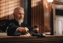 Judge holding gavel in a courtroom setting.