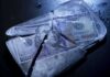 Hundred dollar bills frozen in cracked ice block