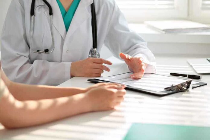 50075309 featured image Doctor discussing with patient, holding clipboard on desk.