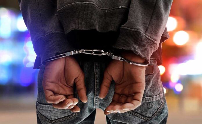 739687099 featured image Person in handcuffs with colorful lights in background.