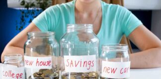 Four labeled jars filled with coins on table