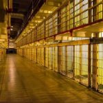 Empty hallway between rows of prison cells