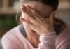 Woman covering face with hand looking stressed