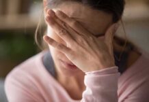 Woman covering face with hand looking stressed