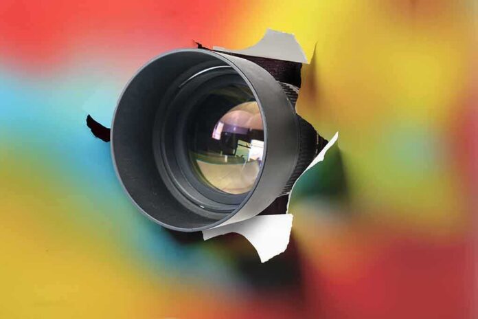 1892209375 featured image Camera lens poking through torn colorful background