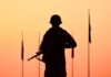 Silhouette of soldier with rifle at sunset