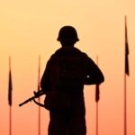 Silhouette of soldier with rifle at sunset