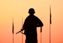Silhouette of soldier with rifle at sunset