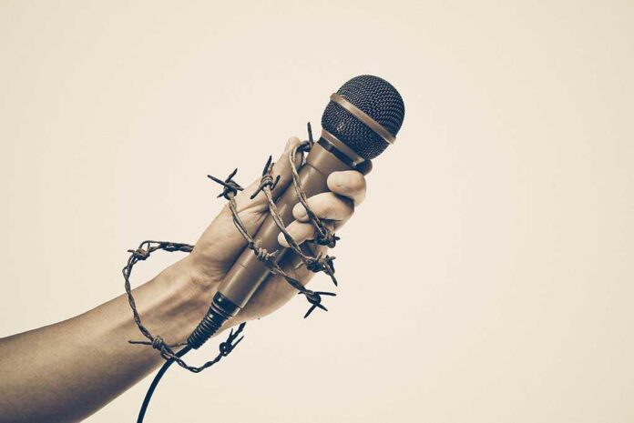 425016769 featured image Hand holding microphone wrapped in barbed wire.