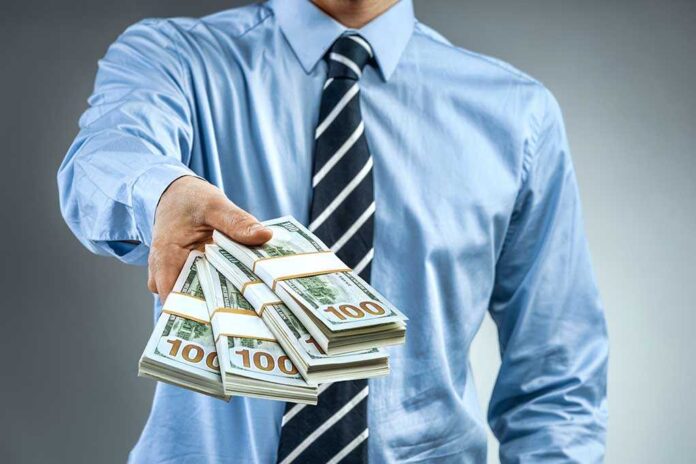 1008204853 featured image Person handing over a stack of money for investment