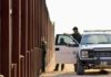 Border patrol agents near a tall metal fence