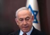 Man in suit with Israeli flag in background