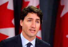 Man speaking in front of Canadian flags