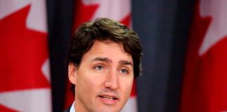 Man speaking in front of Canadian flags