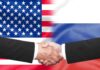 Hands shaking in front of USA and Russia flags