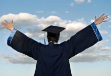 Graduate in cap and gown celebrates under cloudy sky