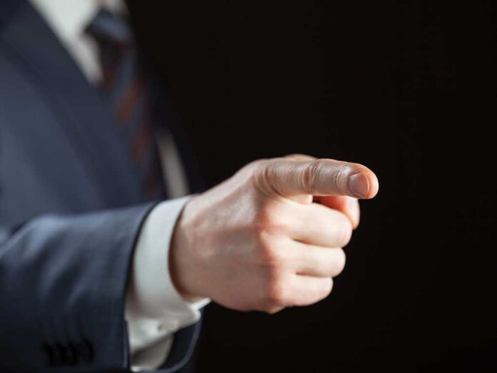 128319779 featured image Person pointing with finger, wearing a suit.