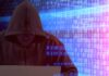 Person in hoodie using laptop, surrounded by digital code.