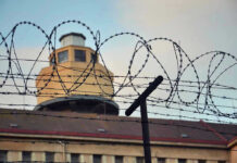Barbed wire in front of a prison tower.