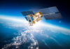 Satellite orbiting Earth with moon in background