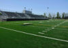 Empty football field with bleachers in background