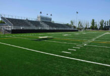 Empty football field with bleachers in background