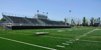 Empty football field with bleachers in background
