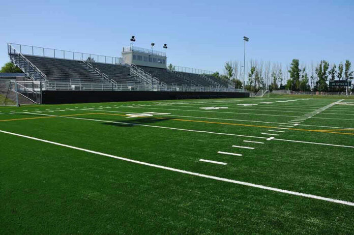55132081 Empty football field with bleachers in background
